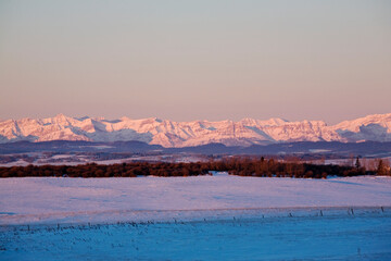 Obraz premium Sunrise Over Canadian Rockies And Snowy Field; Cochrane, Alberta, Canada