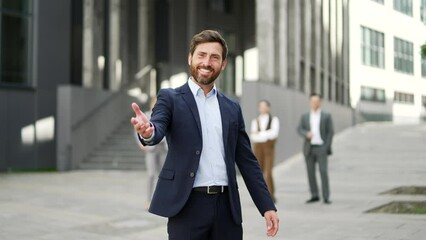Confident happy business man invites you to join the team near the entrance to the business office building. Employee, hr entrepreneur, investor calls to invest or hiring people look at camera Join Us