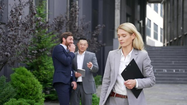 Coworkers employees group man Whispering Behind Back. men mock colleagues are gossiping at background behind young specialist worker workmate bullying or sexism problem at work place in office outside