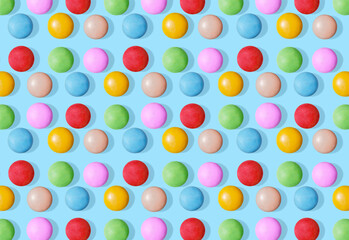 Pattern of rainbow candies on blue pastel background