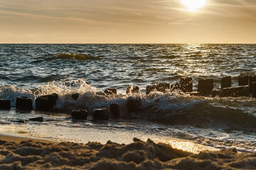 Maritime sunset. The waves are crashing against the breakwaters. Spray from the sea waves.