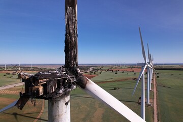 Aerial side view of the Striking Panorama of a Burned-Out Wind Turbine in a wind farm. Close-up on wind turbine destroyed by fire after a lightning strike. Windmill over heated and set fire. Spain