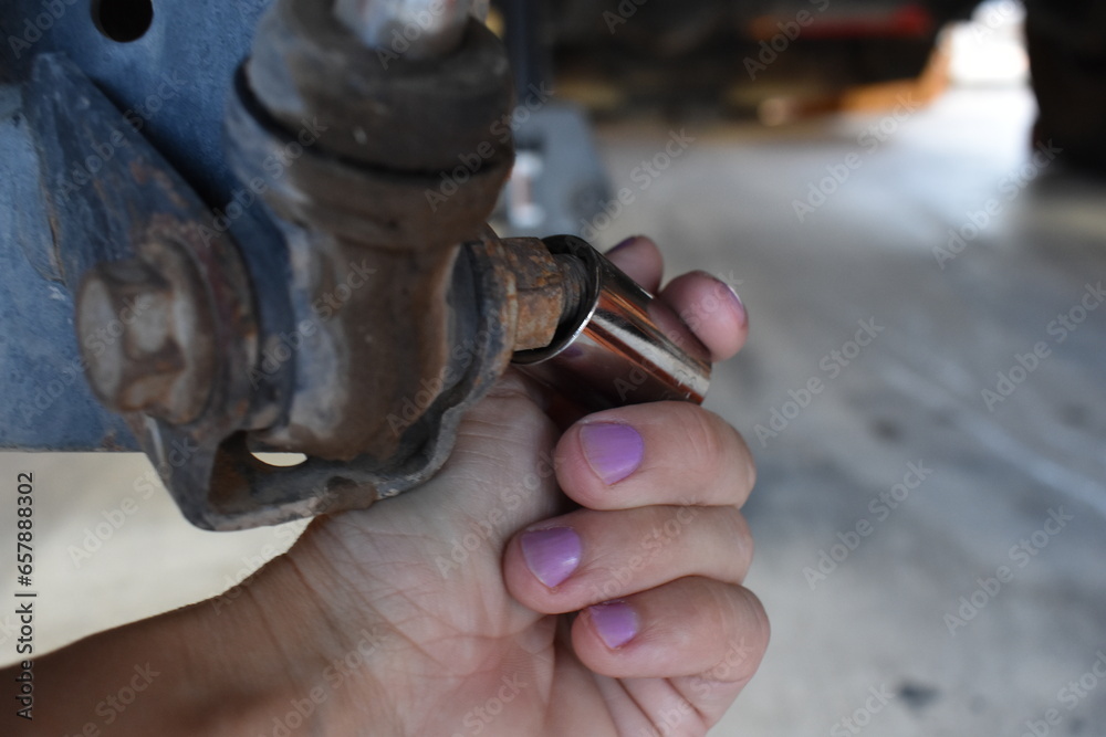 Wall mural female hand fitting a socket on a bolt, working on car