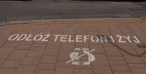 Remove or put down your telephone before crossing the street writen in polish language. Safety...