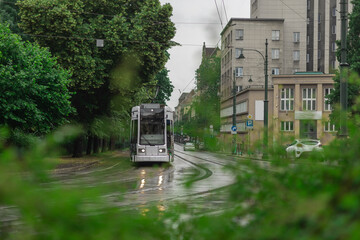 Blue polish tram in the middle of Krakow city on a rainy day. Beautiful picture of a tram, public service transport during a light drizzle rain