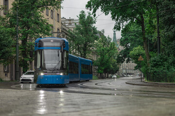 Blue polish tram in the middle of Krakow city on a rainy day. Beautiful picture of a tram, public...