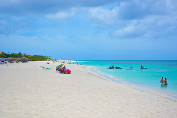 Aruba, Caribbean island. A view on the blue sea and white sand. People sunbathing on the beach. 