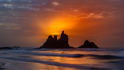 fiery summer sunset behind the typical rocks of benijio beach in the north east of tenerife island - obrazy, fototapety, plakaty