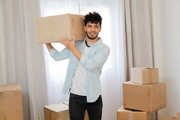 Portrait of young Hispanic man carrying moving boxes - excited young man moving to new home