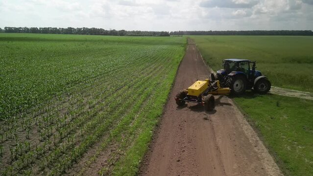 Grader works with tractor and levels the field road
