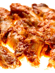 Pile of raw uncooked marinated chicken wings on white background. High quality poultry product with delicate rich flavor. Food supply chain.