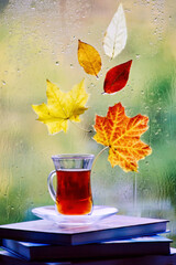A cup of tea with books and autumn leaves