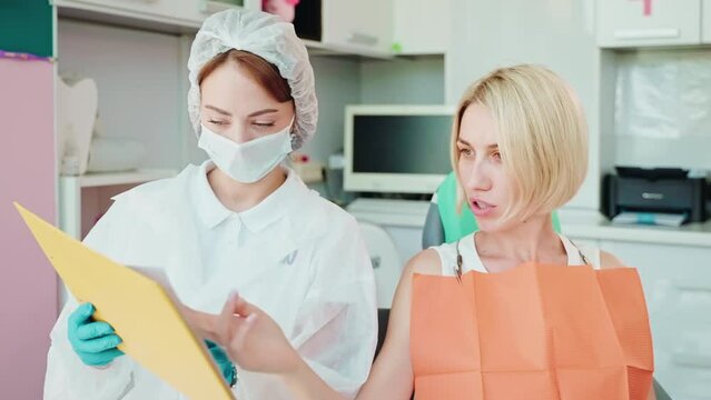 woman patient at dentist appointment, giving questions to female doctor, orthodontist consultation