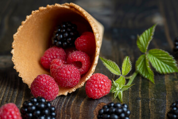 Red ripe raspberries with waffle cups on a black table