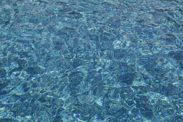 Water ripples on blue tiled swimming pool background. View from above. vacation and summer concept. 