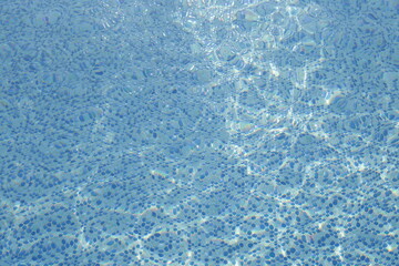 Fototapeta na wymiar Water ripples on blue tiled swimming pool background. View from above. vacation and summer concept. 