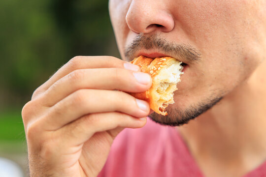 Chewing mouth while eating, guy eats mini puff pastry. Background with selective focus and copy space