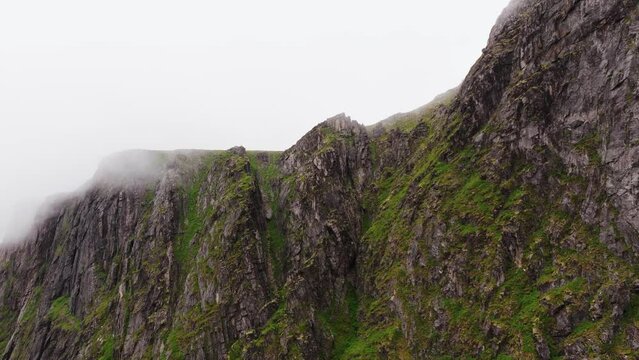 Drone shot - aerial view of mossy mountain wall, rocky coastline in Lofoten islands.