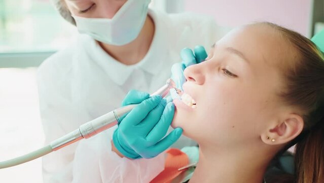 Teen girl on teeth hygienic mechanical clening in stomatology clinic.
