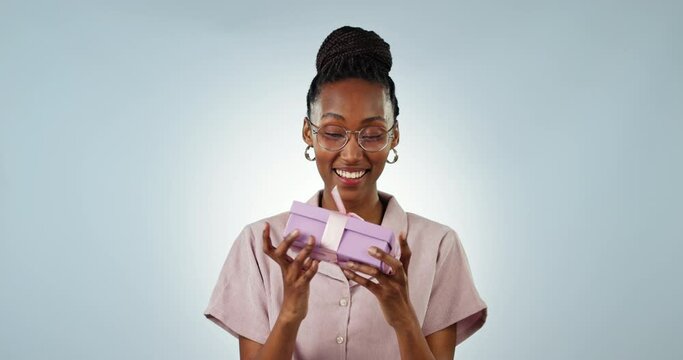 Shake box, excited or face of person in studio isolated on a blue background with product. Happy, guess or black woman with present for party, celebration of holiday or birthday package for giveaway
