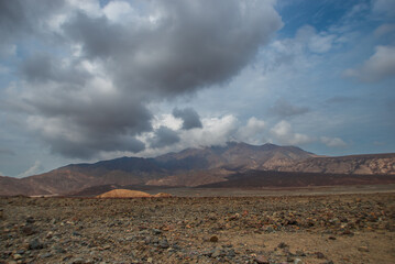 The landscape of a mountainous place with dramatic clouds and rocky ground