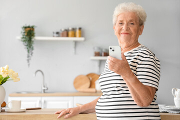 Senior woman using mobile phone in kitchen