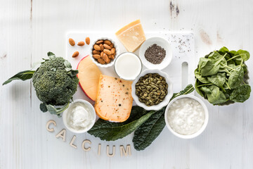Several healthy foods high in calcium on and around a white cutting board.