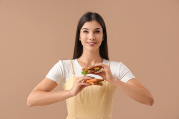 Young woman with tasty sandwiches on color background