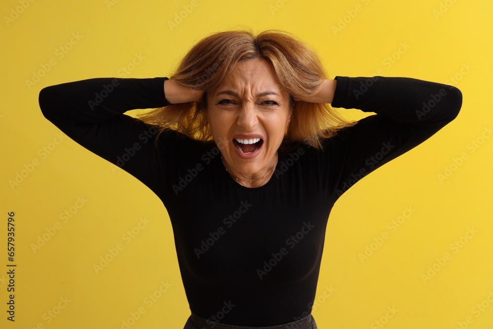 Poster Scared mature woman screaming on yellow background