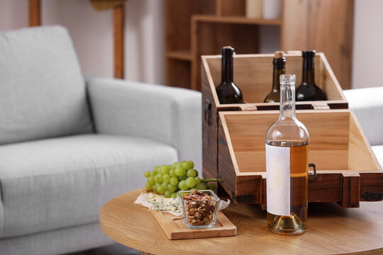Wooden box with bottles of wine and snacks on table in living room