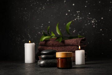 Jar with cream and spa stones on black background