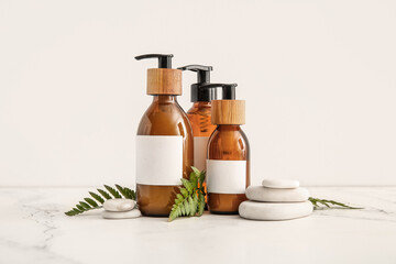 Bottles of shampoo and spa stones on white background