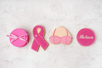 Pink cookies with ribbon, bra, word BELIEVE and gift box on white grunge background. Breast cancer awareness concept - obrazy, fototapety, plakaty