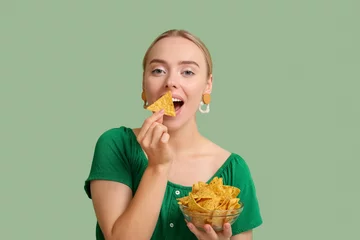 Foto op Canvas Pretty young woman eating nachos on green background © Pixel-Shot