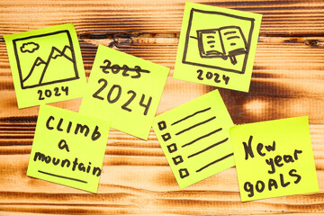 Sticky notes with different goals for 2024 on brown wooden background