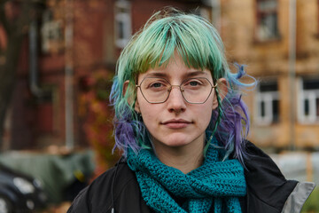 A captivating portrait of a young, interesting girl with striking blue hair, taken in the park in...
