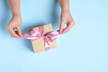 Woman with gift box on light blue background, top view. Space for text