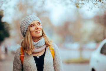 Woman Wearing Beanie and Winter Clothes Smiling Walking Outdoors. Trendy fashionable girl with warming knitwear accessories
