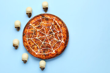 Wooden board with tasty pizza and human skulls for Halloween party on blue background