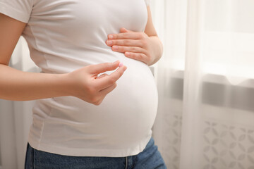 Pregnant woman with pill at home, closeup