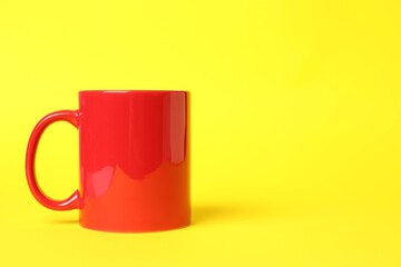 One red ceramic mug on yellow background, space for text