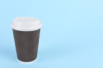 Brown paper cup with plastic lid on light blue background, space for text. Coffee to go