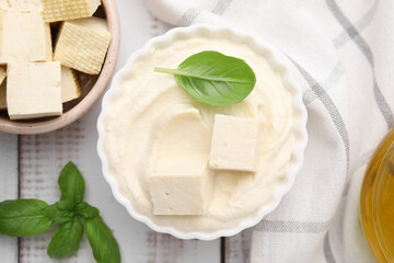 Delicious tofu sauce and basil leaves on white wooden table, flat lay
