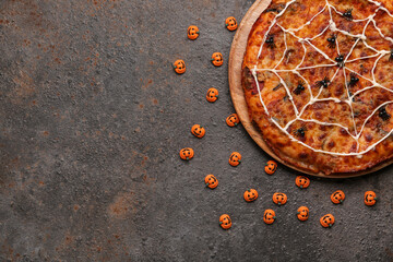 Wooden board with tasty pizza and decorations for Halloween party on grunge background