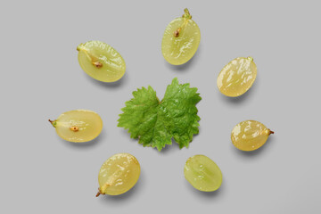 Halves of fresh green grapes with leaf on grey background