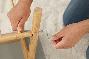 Man with hex key assembling furniture on carpet, closeup