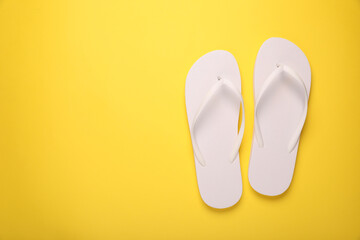 Stylish flip flops on yellow background, top view. Space for text
