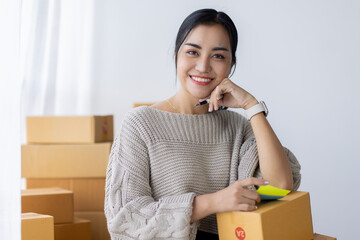 Startup happy Asian woman business owner works with a box at home, prepare parcel delivery SME...