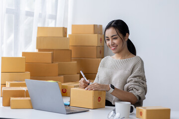 Portrait of Asian young woman SME working with a box at home the workplace.start-up small business owner, small business entrepreneur SME or freelance business online and delivery concept.
