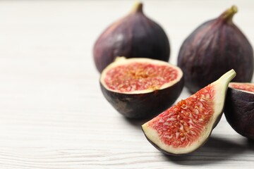 Whole and cut ripe figs on white wooden table, closeup. Space for text
